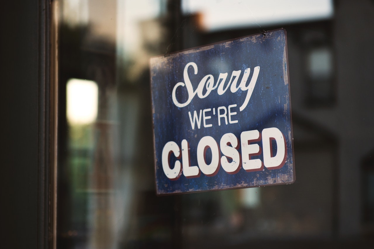 'Sorry we're closed' sign displayed outside an empty shop