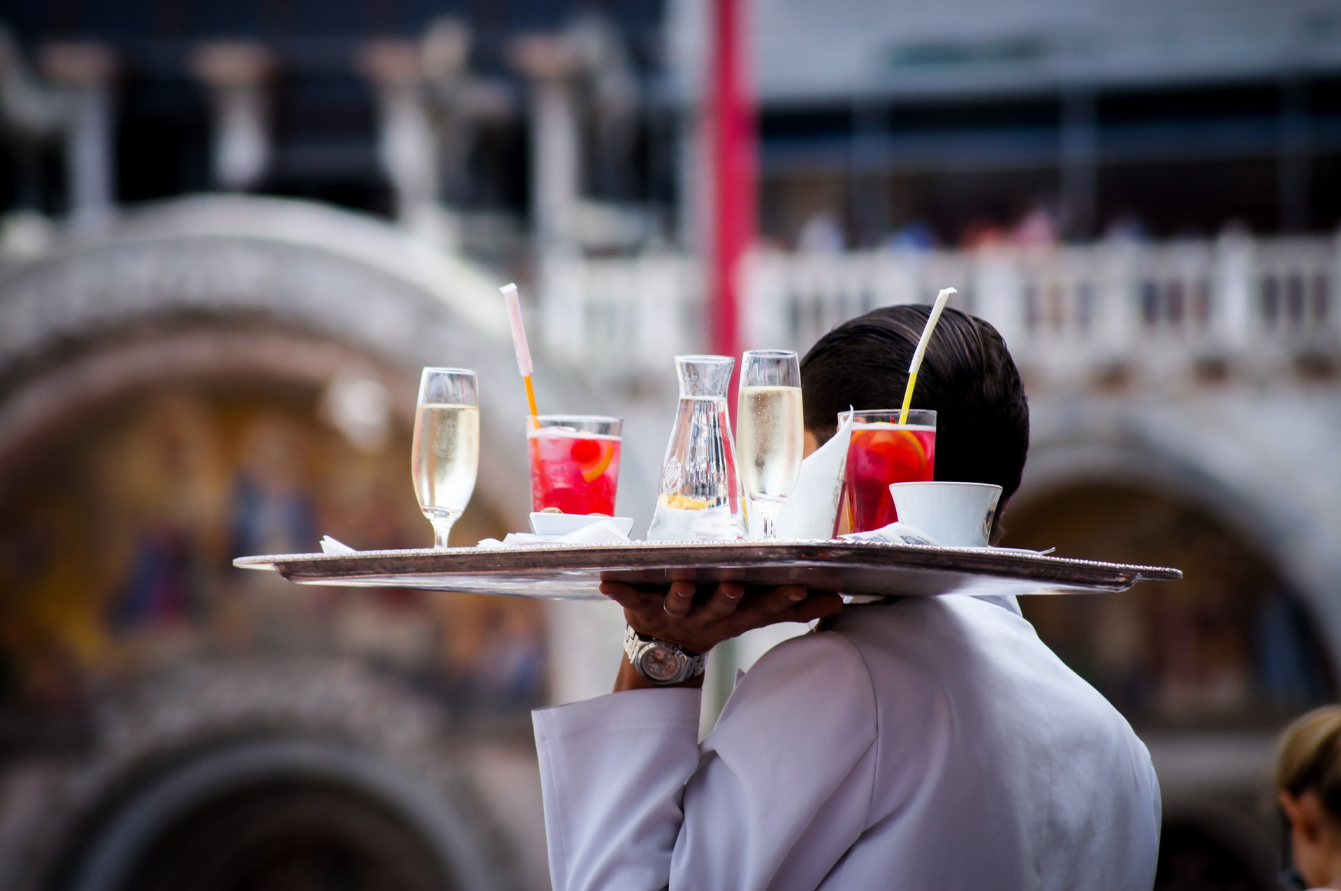 waiter carrying a tray full of drinks and cocktails