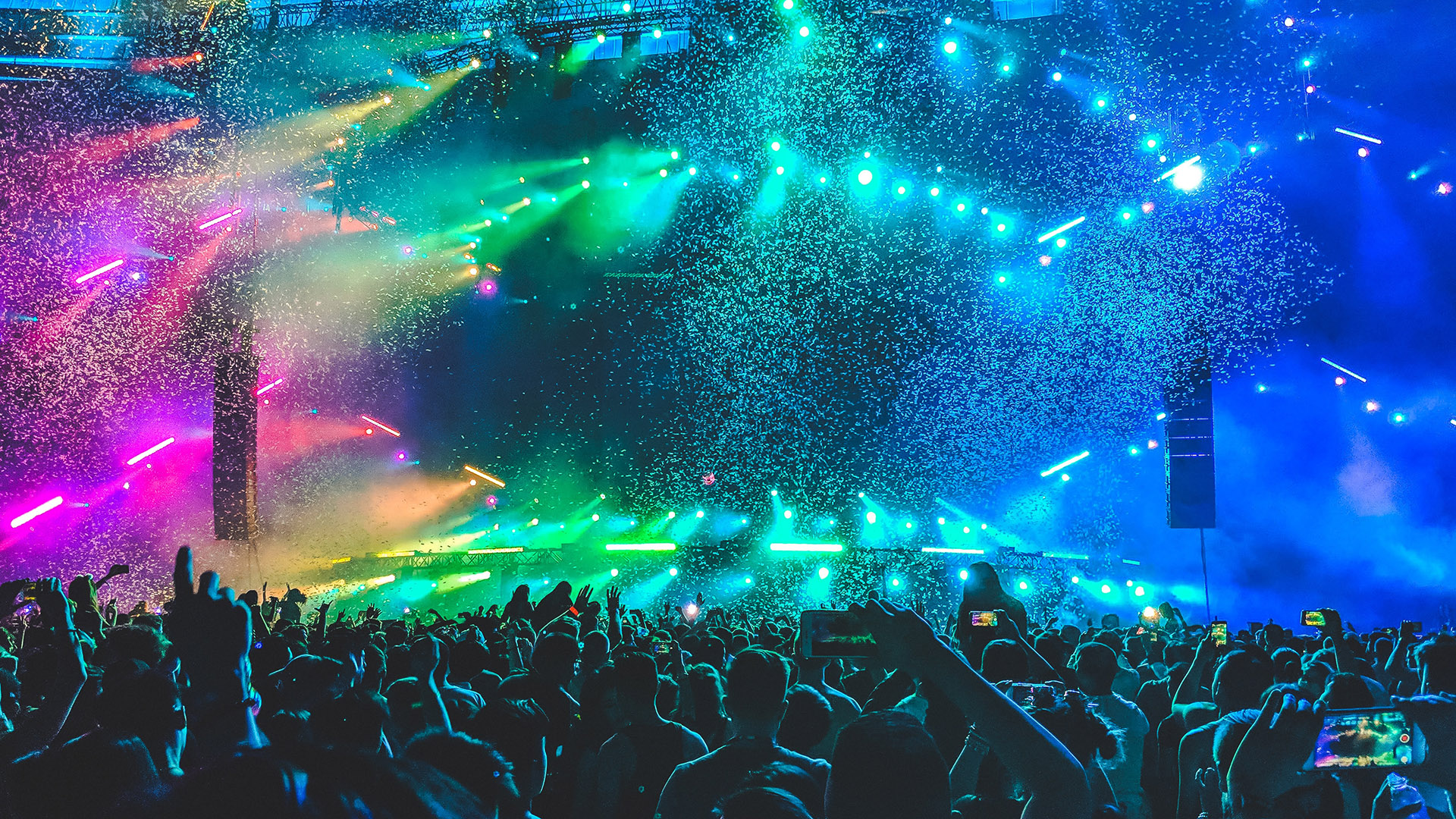 Group of people dancing at a nightclub party with rainbow lights for eurovision